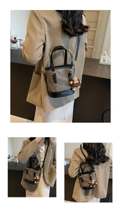 Detail of grey canvas bucket bag with black leather trim and plush monkey charm