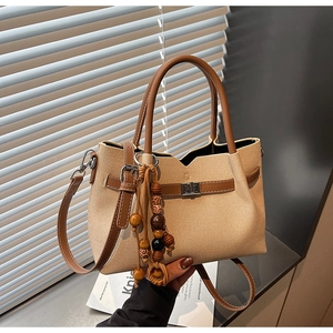Détail du sac cabas en toile et cuir marron avec breloque en bois et fermoir en métal