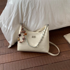 Détail du sac matelassé crème avec fermoir rotatif argenté et breloque perlée