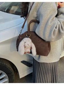 Detail of dark brown vintage Boston bag with plush rabbit pendant and silver metal hardware