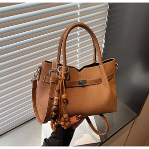 Détail du sac à main marron avec fermoir tournant en métal et pompon en perles
