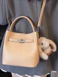 Sac à main minimaliste en cuir beige avec fermoir métallique et breloque lapin