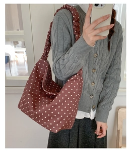Dettaglio della borsa tote bordeaux a pois con tracolla a pieghe indossata dal modello