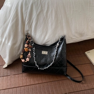 Détail du sac hobo matelassé noir avec fermoir argenté et breloque en perles colorées