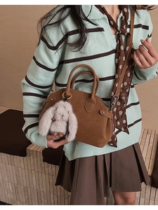Detailed close-up of brown vintage shell bag with a grey plush rabbit charm and textures