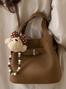 Brown litchi leather bucket bag with plush bear charm and elegant beaded pendant