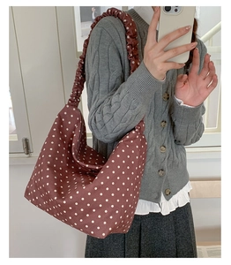 Dettaglio della tracolla a pieghe e dei pois bianchi sulla borsa tote rossa elegante