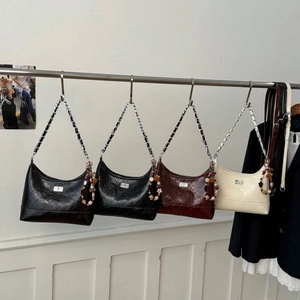 Détail de sacs à bandoulière matelassés en noir, marron et crème avec breloques perles
