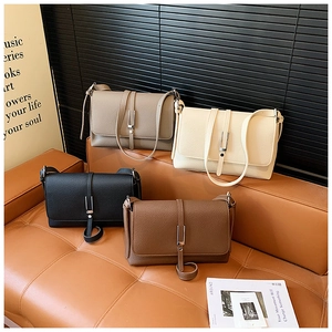 Detail view of four textured leather crossbody bags in grey, beige, black, and caramel