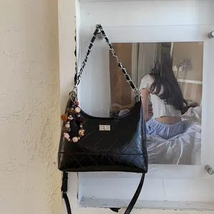 Détail du sac à bandoulière noir matelassé avec chaîne argentée et breloque petit ours