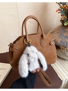 Brown leather handbag detail featuring a soft rabbit plush charm and sleek top handle