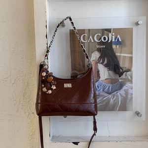 Détail du sac matelassé marron foncé avec bandoulière chaîne et breloque en forme d'ours