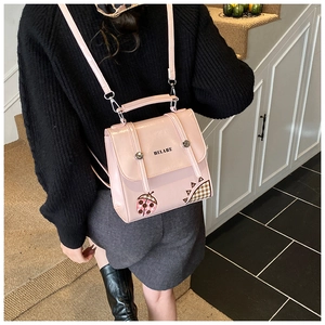 Detailed view of a pink patent leather backpack with cute embroidery and ladybug patch