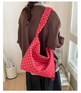 Scatto lifestyle di una borsa tote rossa a pois portata a spalla in un ambiente accogliente