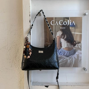 Détail du sac à bandoulière matelassé noir avec fermoir tournant en métal et chaîne