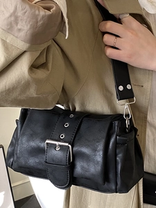 Chic black leather shoulder bag with decorative buckle and wide rivet strap in matte finish