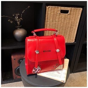 Detail view of red leather retro backpack with black text and ladybug plaid patch