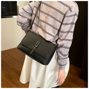 Detail of black lychee texture leather shoulder bag with silver metallic buckle closure