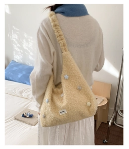 Dettaglio di una borsa tote in peluche crema con toppe a stella ed etichetta Petit Merci