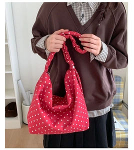 Dettaglio della borsa tote rossa a pois con manico arricciato e design spazioso