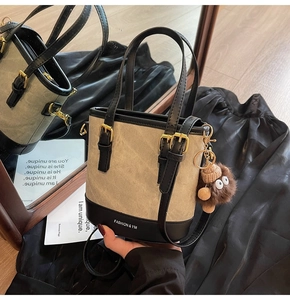 Detail view of canvas bucket bag with black leather trim and cute brown plush monster charm