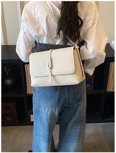 Model view of cream white leather shoulder bag featuring a silver metal buckle and strap