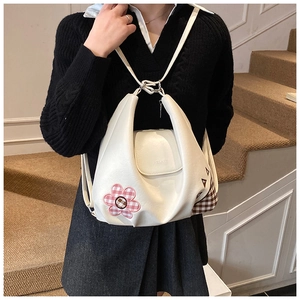 Detailed view of white faux leather half-moon bag featuring a pink plaid flower patch