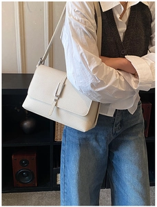 Detail shot of a white lychee grain leather shoulder bag with a sleek silver buckle clasp