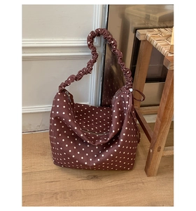 Dettaglio di borsa tote in tela rossa a pois bianchi con eleganti spalline pieghettate