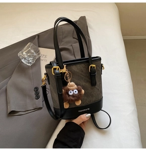 Detail view of canvas bucket bag with leather trim and cute plush monster charm