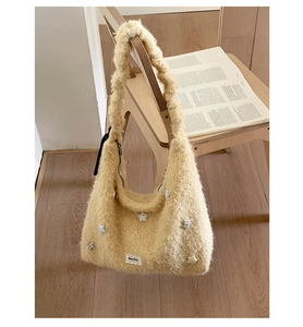 Dettaglio borsa tote in peluche crema con stelle appesa a sedia in legno