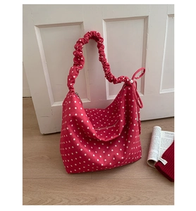 Vista dettagliata della borsa tote in tela a pois rossi con elegante tracolla a balze