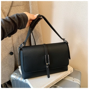 Detail of black lychee grain leather shoulder bag with a silver metal bar lock clasp