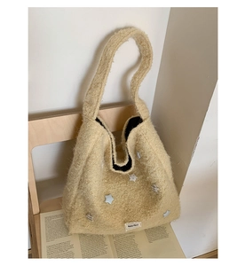 Dettaglio borsa tote in lana di agnello con toppe a stella e etichetta Beyou Morel su un libro