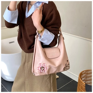 Detail view of pink leather tote featuring vintage plaid fabric patches and brand logo