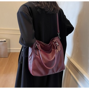 Detail view of burgundy leather tote bag with silver hardware on model back