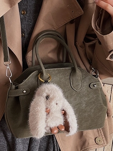 Deep green leather shell handbag with plush rabbit pendant and gold metal buckle accents