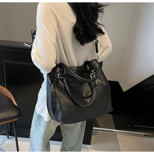 Detailed view of the large black pleated leather tote bag with silver hardware on a model