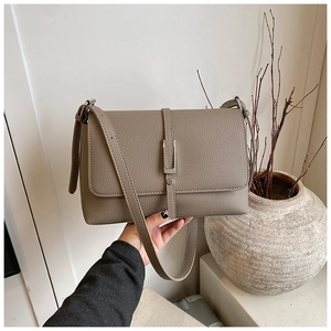 Detailed close-up of elephant grey lychee textured leather bag with silver metal buckle