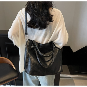 Detail of black PU leather tote bag with subtle pleated texture and adjustable strap