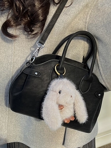 Minimalist black matte leather crossbody shell bag with a cute pink plush bunny charm
