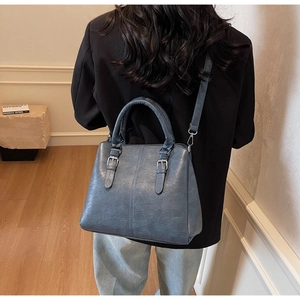 Détail du sac à main bleu en cuir grainé avec boucle argentée et bandoulière fine