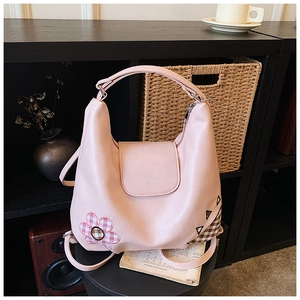 Detail of pink shoulder bag with flower embroidery and brand logo in lifestyle setting