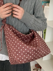 Borsa a tracolla minimalista in tela marrone a pois da donna indossata da modella