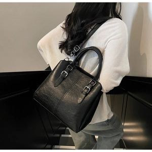 Gros plan sur un sac noir montrant le grain du cuir et les boucles argentées
