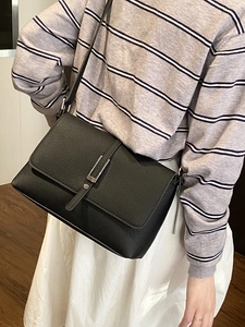 Classic black litchi pattern leather crossbody bag with silver buckle worn by a model