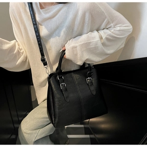 Détail d'un sac à main noir en cuir PU avec boucles argentées et bandoulière amovible