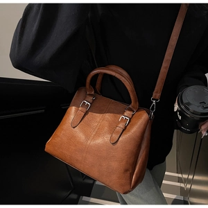 Détail du sac à main vintage marron en cuir avec texture fine, boucles argent et bandoulière