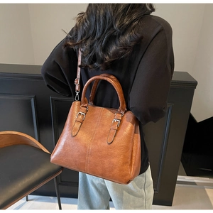 Détail d'un sac à main marron vintage avec doubles poignées et surpiqûres élégantes