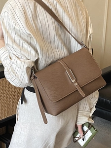 Deep brown minimalist faux leather crossbody bag with silver buckle worn by a model